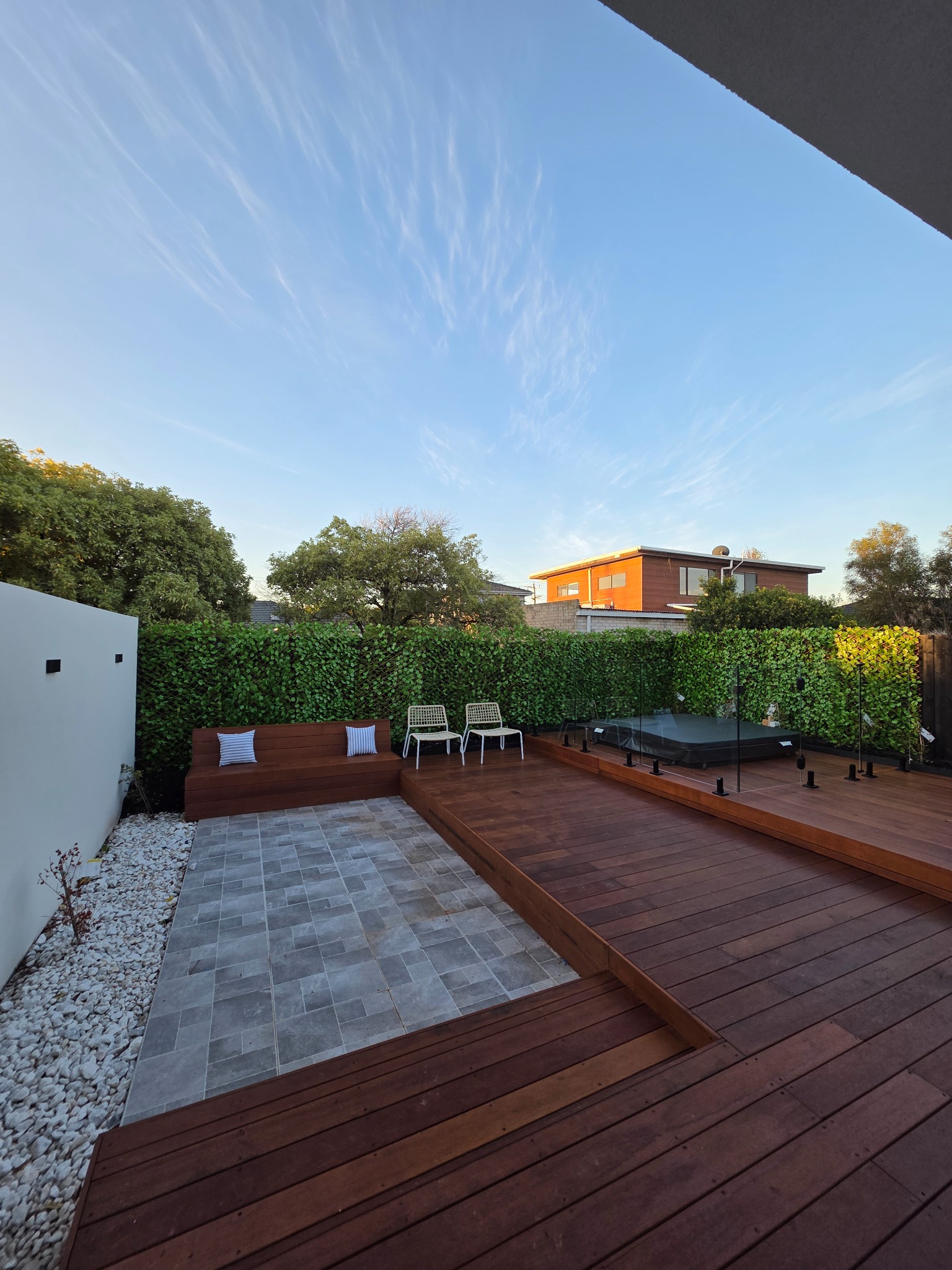 Completed multi-level timber deck with integrated seating, paving and glass pool fencing